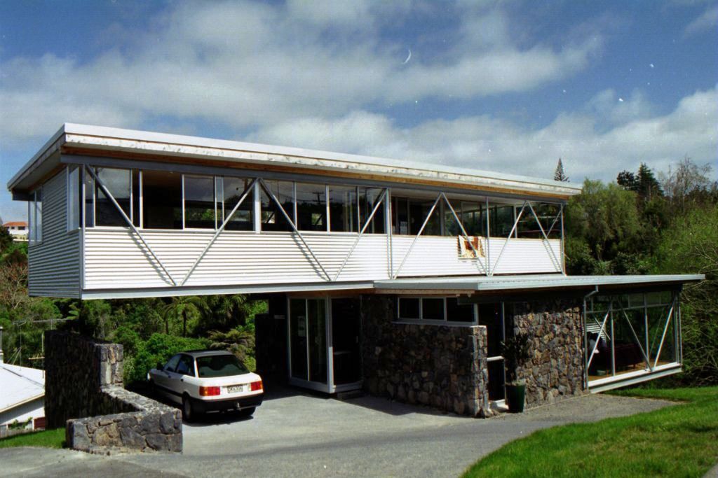 Two-level house with steel structure and stone base on a steep site